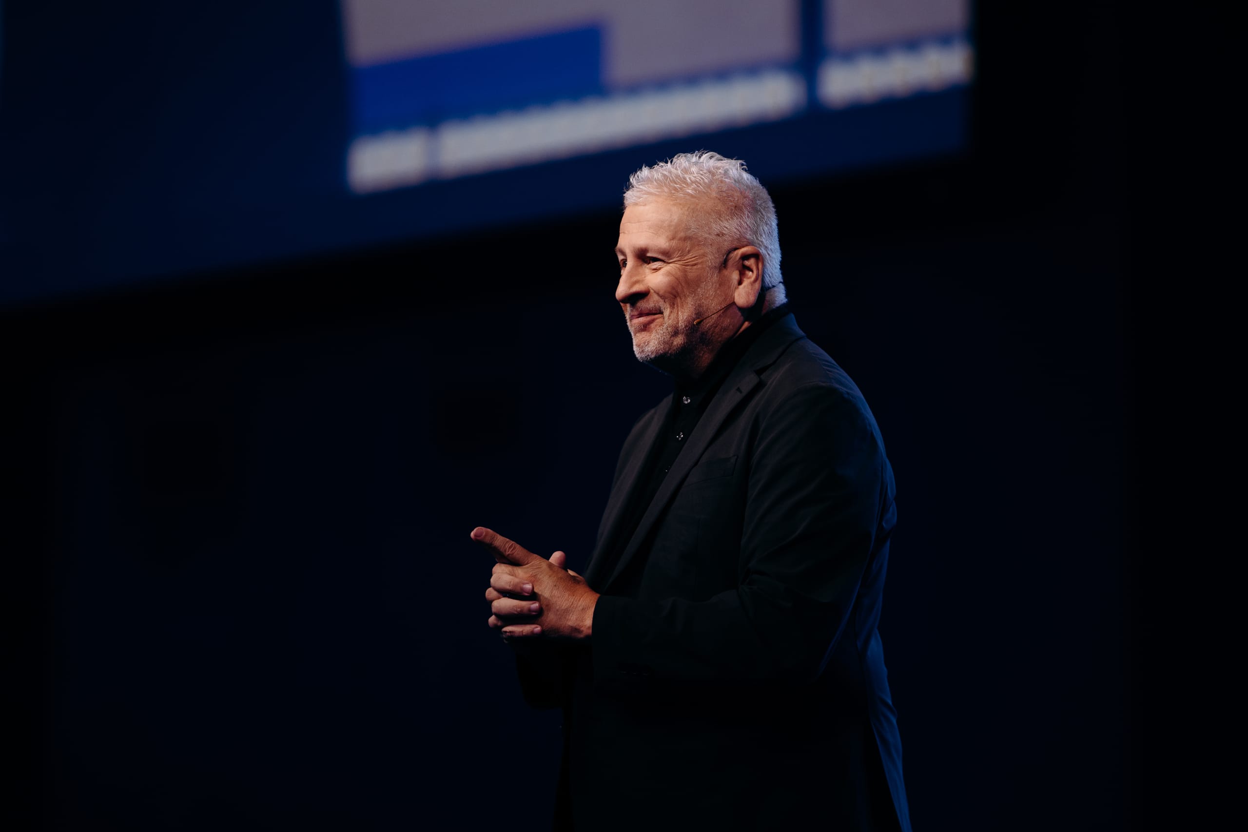 Keynote speaker gesturing on a dark stage