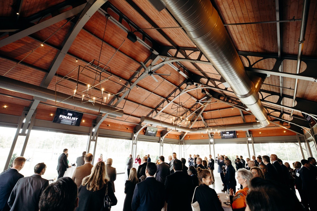 Business crowd under a timber pavilion roof at an awards program