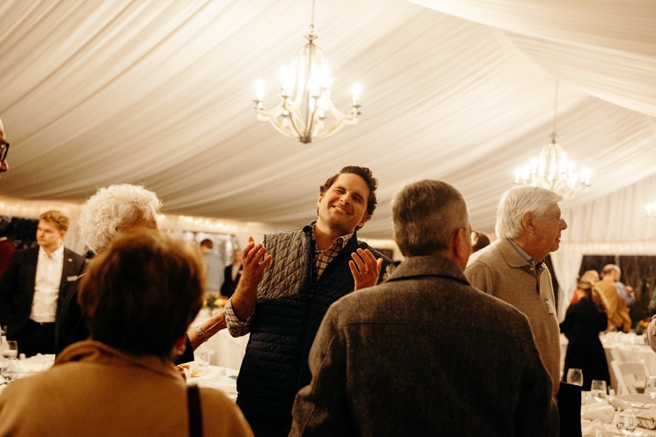 Guest greeting others at a tented dinner
