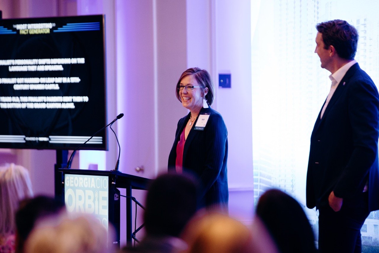 Presenter at a lectern in violet light