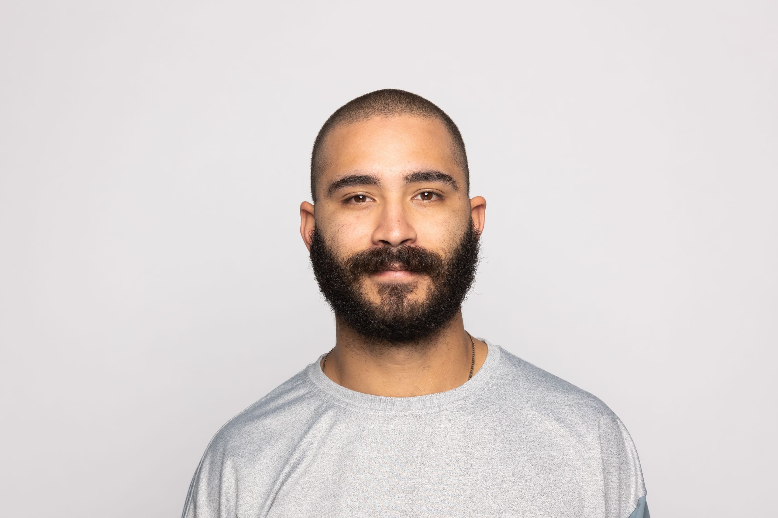 Studio headshot of a bearded man in a grey sweatshirt