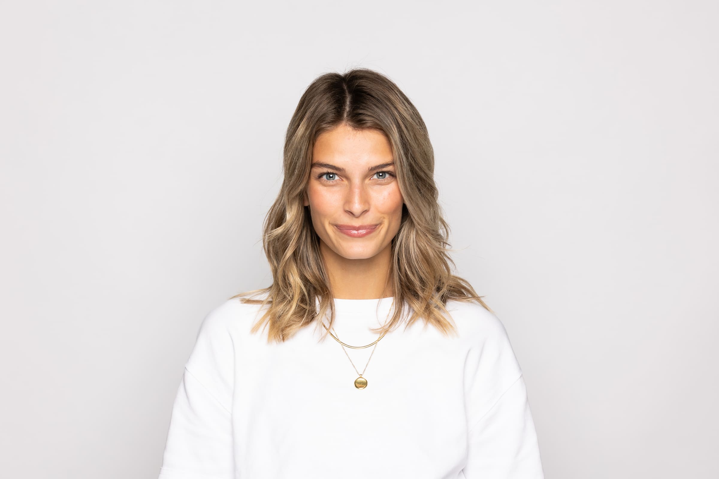 Studio headshot of a woman in a white top