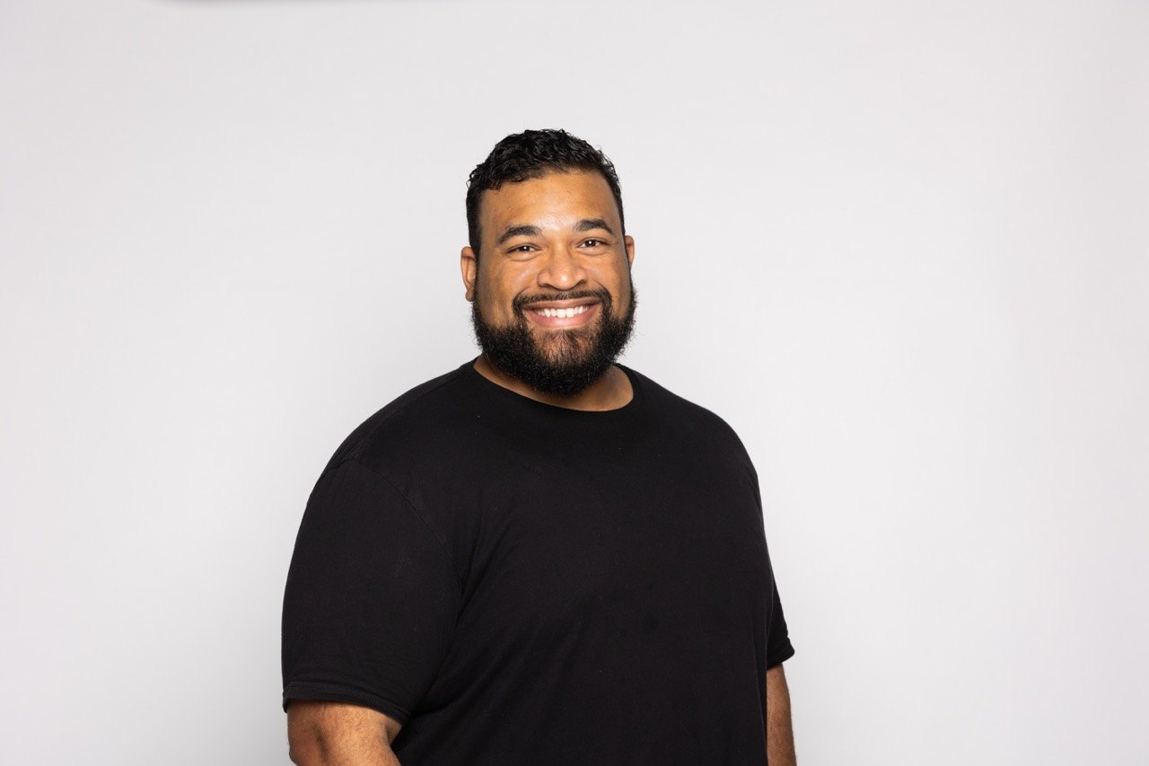 Studio headshot of a man in a black t-shirt