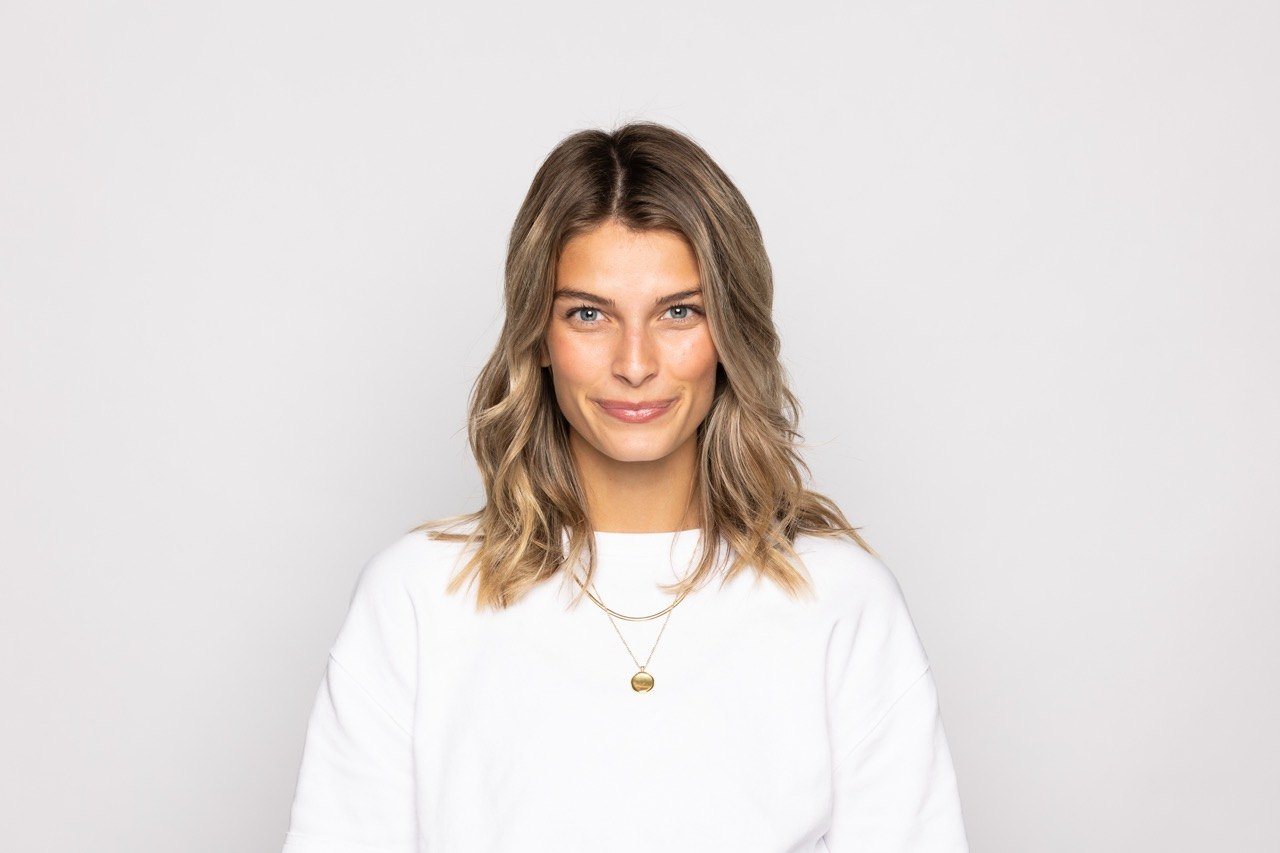 Studio headshot of a woman in a white top