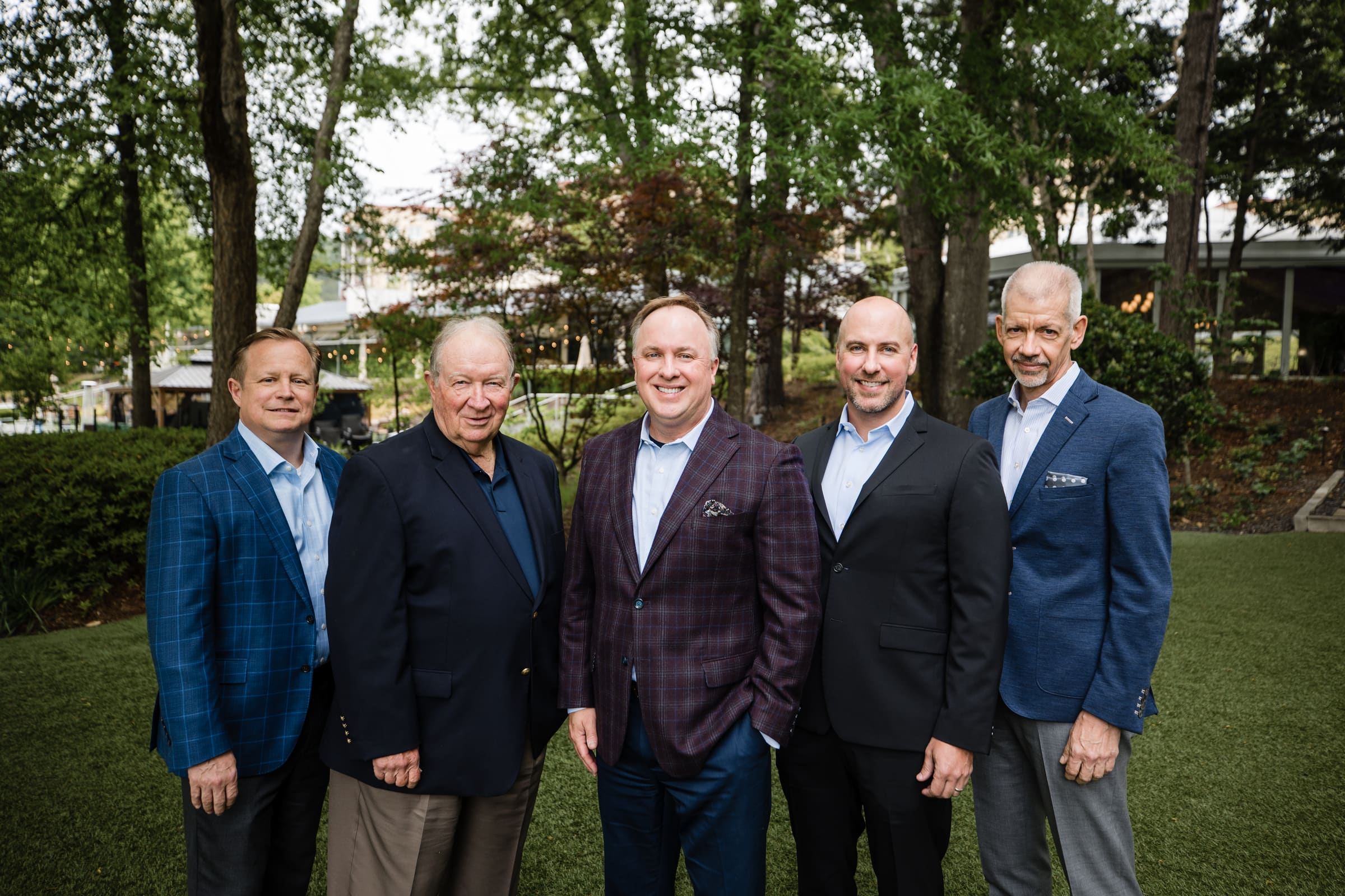 Team photo of five colleagues in blazers on a garden lawn